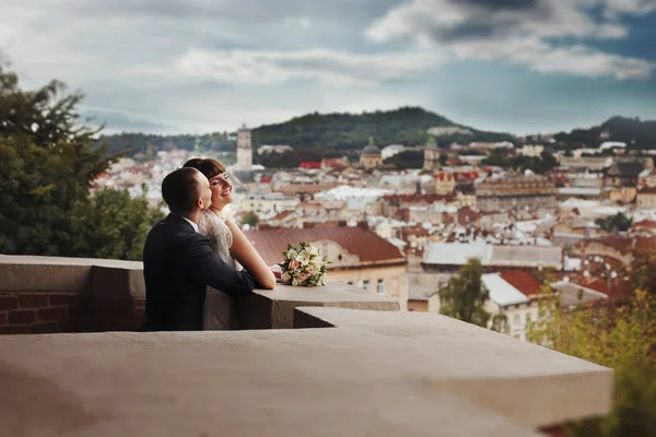 Groom kisses smiling bride from behind standing on the balcony — Stock Photo, Image