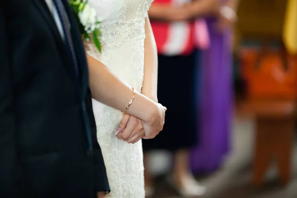 Невеста держит руки закрытыми во время церемонии в церкви — стоковое фото