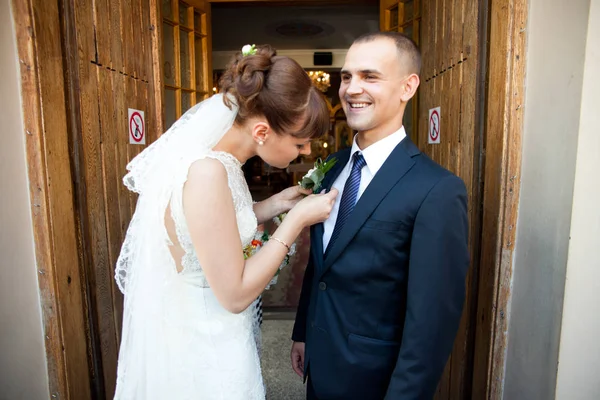 Goom lacht terwijl bruid een corsages aan zijn jasje pinnen — Stockfoto