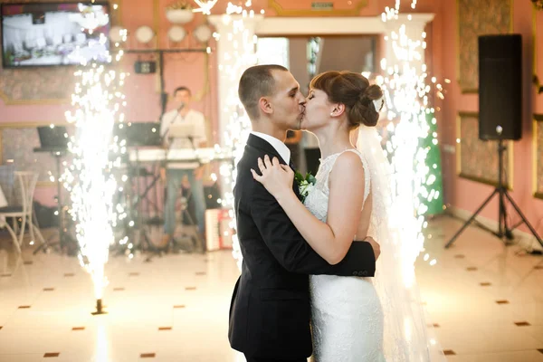 Bride and groom kiss standing in the middle of restaurant hall i — Stock Photo, Image