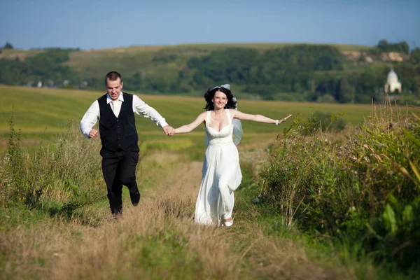 Жених и невеста, раздвигая руки, бегут по высоте — стоковое фото