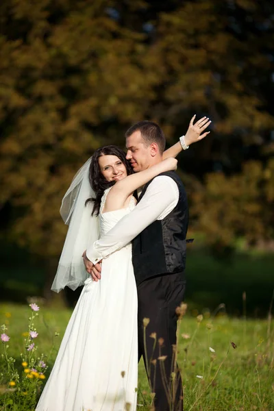 Sposa sorride ampia mentre si appoggia a uno sposo e torcendo la mano — Foto Stock