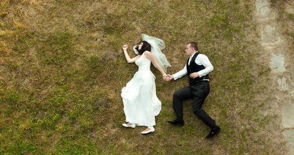 Les jeunes mariés mentent comme marchant sur l'herbe — Photo