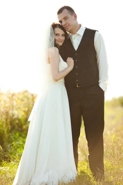 Hoog bruidegom in zwarte gilet vormt met mooie bruid op de — Stockfoto