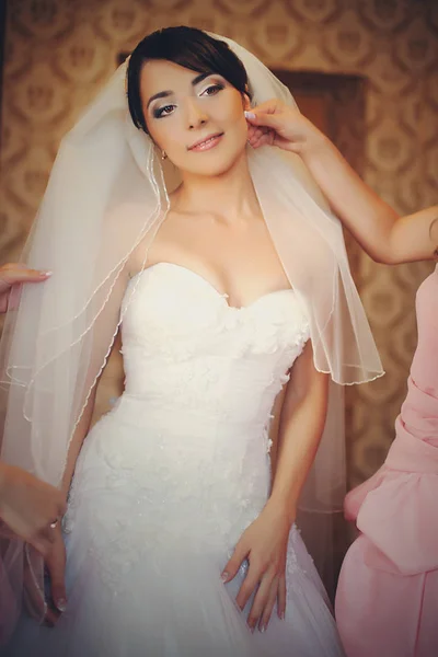 Brautjungfern berühren den Schleier, während die Braut im Zimmer posiert — Stockfoto