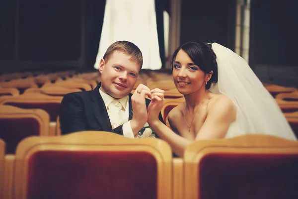 Sposa e sposo si tengono le mani sotto forma di cuore seduto in — Foto Stock