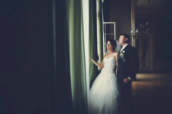 Bride and groom look up in the sky through the window — Stock Photo, Image