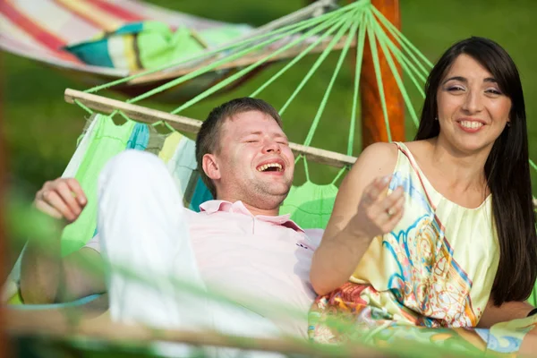 Young couple laughs sitting on the hammock
