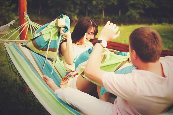 Brunette throws a pillow in a man lying on the hammock — Stock Photo, Image