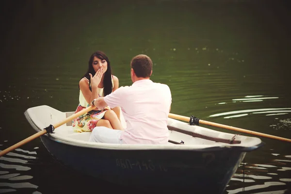 Morena se senta na frente de um homem em um barco — Fotografia de Stock