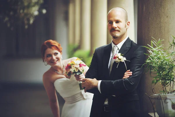 La mariée regarde par-dessus son épaule pendant que le marié l'attend — Photo