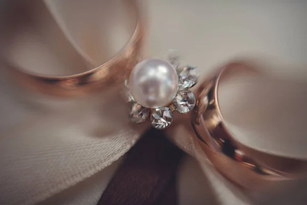 Blurred picture of wedding rings lying over the pearl brooch