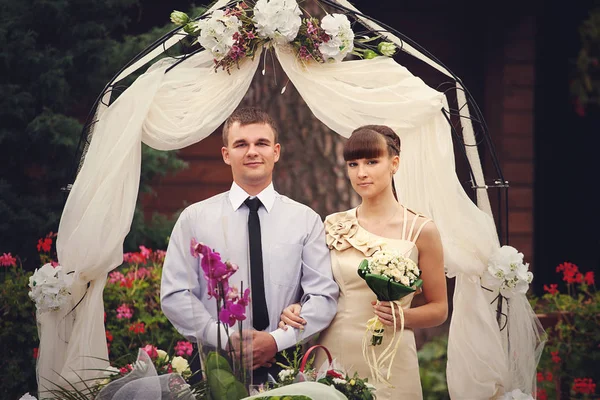 漂亮的新婚夫妇站在米色的祭坛前面 — 图库照片