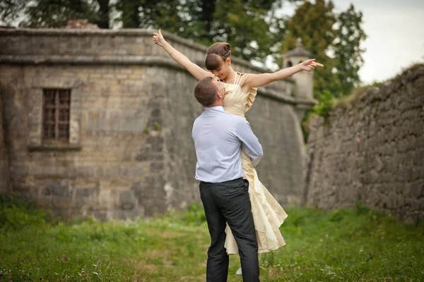 Man whirls a stunning lady standing between stone walls — Stock Photo, Image