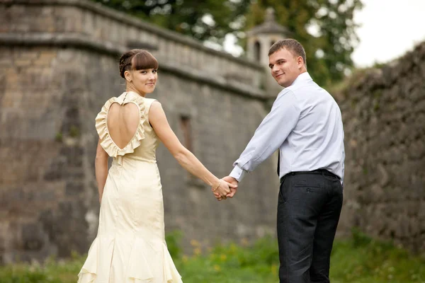 Prachtige paar kijkt over hun soulders samen hand in hand — Stockfoto