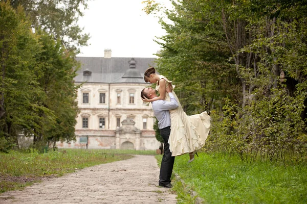 Happy man raises a lady up standing on the path in park — Stock Photo, Image
