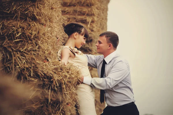 Mann steht vor einer Frau, während sie sich ans Heuhaufen lehnt — Stockfoto