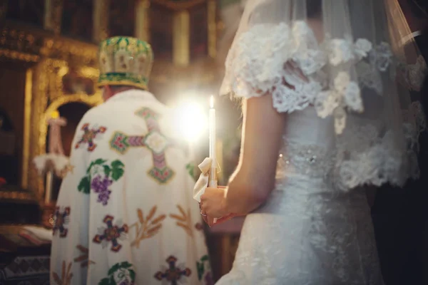 A look from bride\'s back on the burning candle in her hands