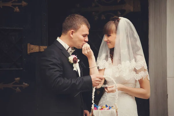 Groom kisses bride's fingers standing before old black doors — Stock Photo, Image
