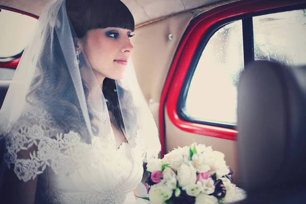 Stunning bride looks far away while driving in the car — Stock Photo, Image