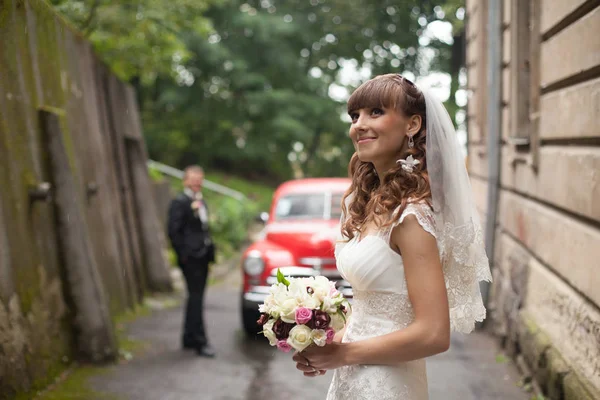 Daydreaming sposa si trova nella parte anteriore della vecchia auto rossa — Foto Stock