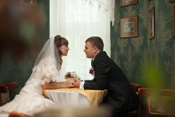 Свадебная пара сидит за кофейным столиком в зеленом зале — стоковое фото
