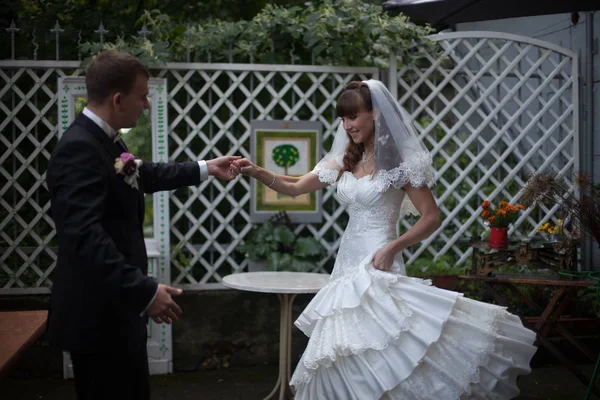 Groom gira uma noiva de pé no quintal branco — Fotografia de Stock