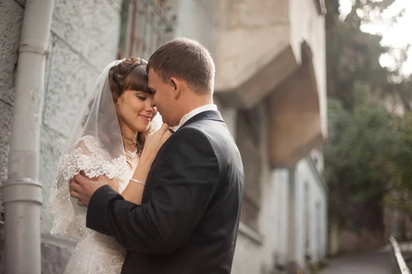 Bräutigam hält zarte Braut im Arm, die vor weißem hou steht — Stockfoto