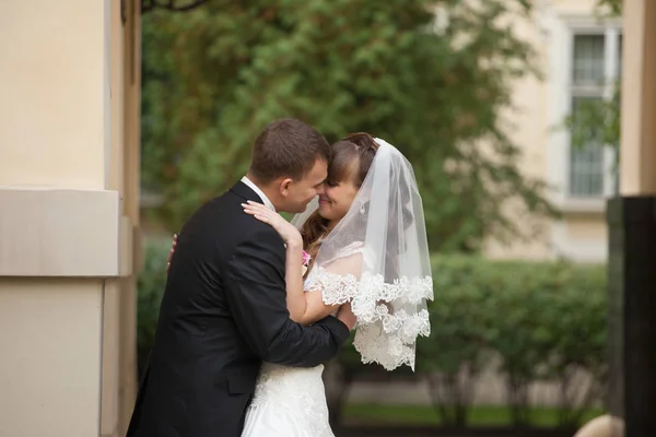 Bräutigam versteckt Braut in seinen Umarmungen beim Küssen draußen — Stockfoto