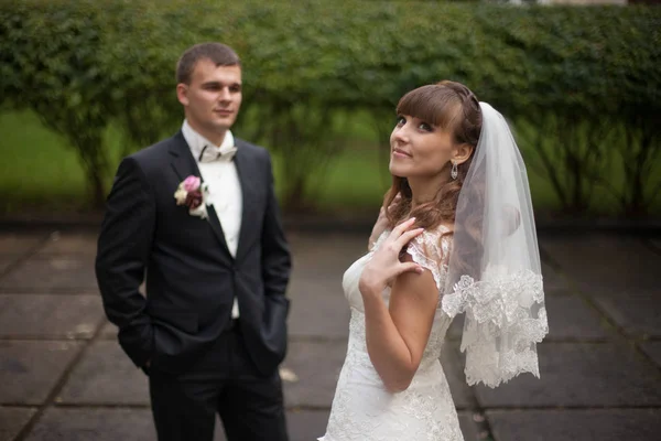 Lächelnde Braut blickt in den Himmel, während der Bräutigam auf dem Rücken wartet — Stockfoto