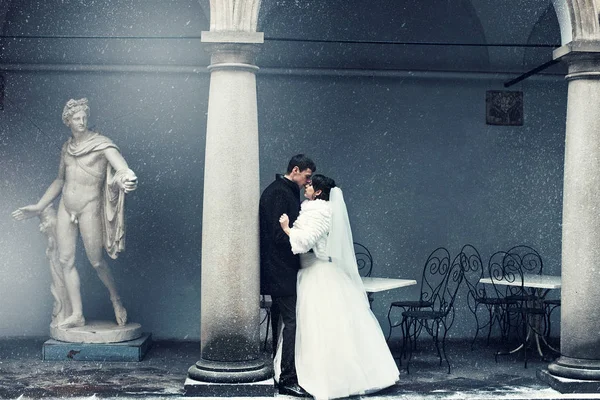 Imagem em tons azuis de recém-casados beijando atrás de um pilar, enquanto — Fotografia de Stock