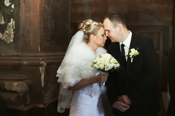 Menyasszony és a vőlegény hajlik a fej-fej a háta mögött a pillér — Stock Fotó