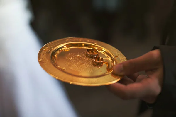 Чоловік тримає золоту тарілку з розкішними обручками — стокове фото