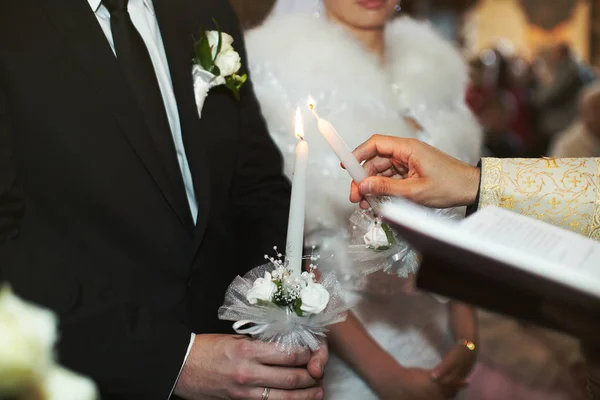 Priester zündet eine Kerze von der Kerze an, die der Bräutigam während der Zeremonie hält — Stockfoto