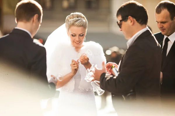 Bruden håller en champagne fluet medan män i svarta kostymer omger — Stockfoto