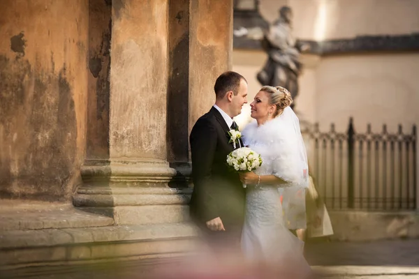 Casal apaixonado posa atrás de um prédio antigo — Fotografia de Stock