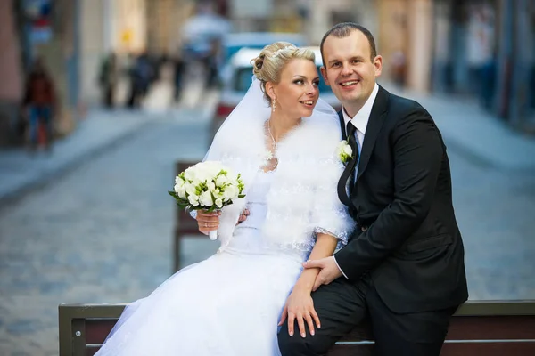 Sposa si appoggia a uno sposo mentre si siedono sul retro di una panchina — Foto Stock
