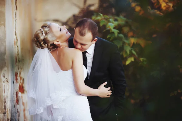 Bruidegom kussen Bruidskamer schouder staande aan de voorkant van een verwoeste — Stockfoto