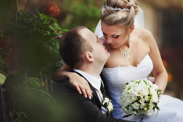 Einen Moment vor einem Kuss zwischen Braut und Bräutigam, während sie auf sitzt — Stockfoto