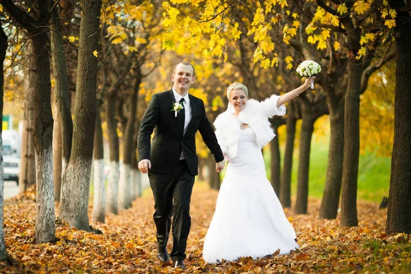 Sposa alza una mano con bouquet come un vincitore mentre cammina arguzia — Foto Stock