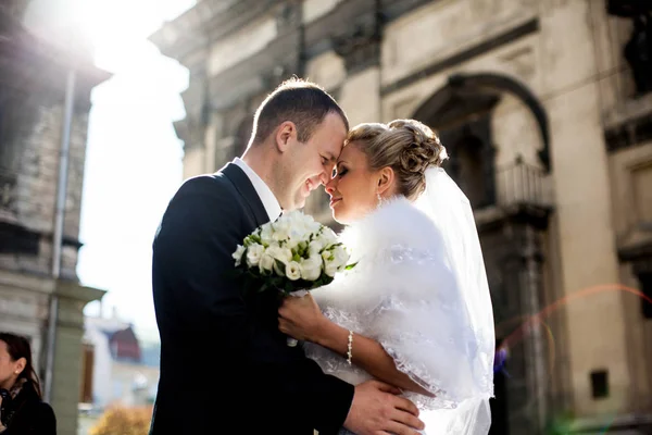 Groom sorri abraçando noiva bonita nos raios do sol da manhã — Fotografia de Stock