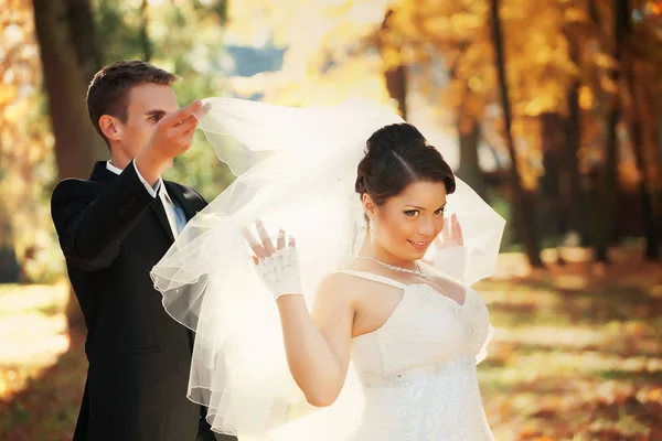 Bräutigam hilft hübscher Braut, ihren Schleier anzupassen — Stockfoto