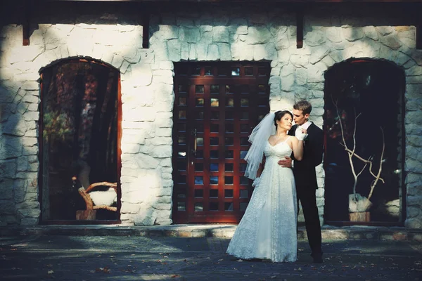 Bonito homem abraça uma noiva por trás de pé na frente de um — Fotografia de Stock