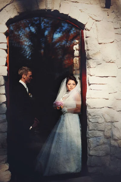 Bräutigam schaut Braut an, während sie sich ans Fenster lehnt — Stockfoto