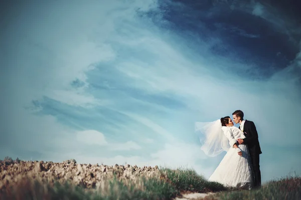Céu lindo se espalha sobre um casal de casamento deslumbrante beijando em um — Fotografia de Stock