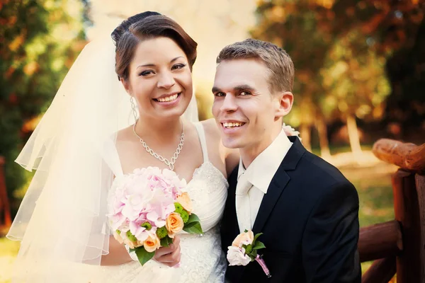 Porträt eines glücklichen Hochzeitspaares auf der Bank in einem Au — Stockfoto