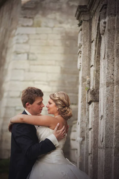 Novio sostiene rubia novia tierna de pie detrás de un hermoso arco —  Fotos de Stock
