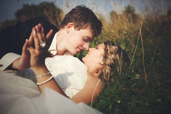 Bräutigam lehnt sich an eine Braut, die auf dem grünen Gras liegt — Stockfoto