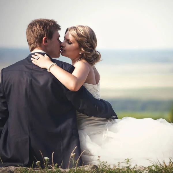 Braut lehnt sich an die Schulter des Bräutigams und küsst ihn im Gras — Stockfoto