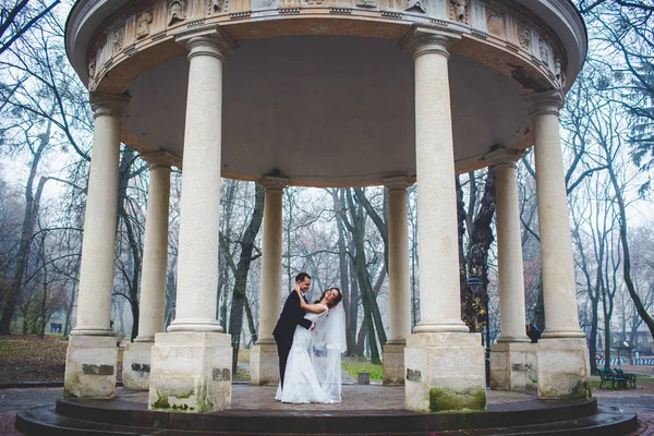 Sposo piega sposa sopra in piedi sotto il portico di pietra — Foto Stock